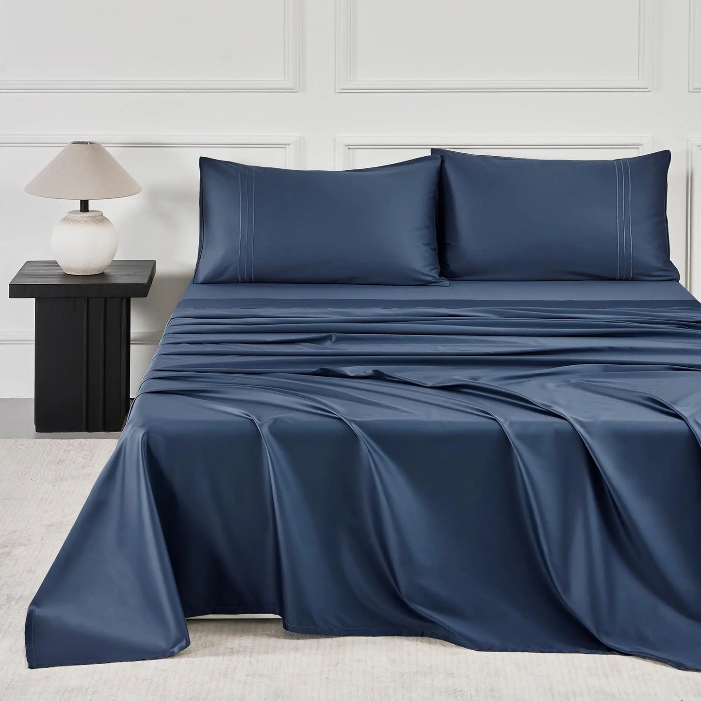 JELLYMONI Soft Cool Cotton Sateen Sheets in a rich navy blue color, artistically arranged on a stylish bed with matching pillowcases for a sophisticated sleep space.