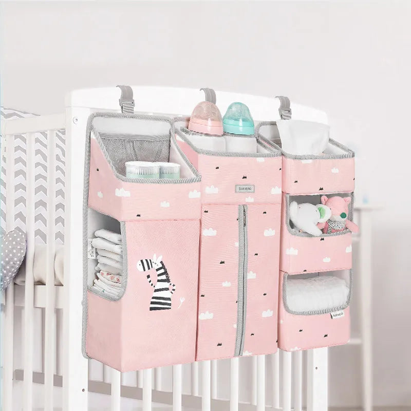 Sunveno Crib Organizer Baby Essentials Within Reach attached to a crib, showcasing a stylish pink design with room for diapers and baby toys, enhancing nursery decor.