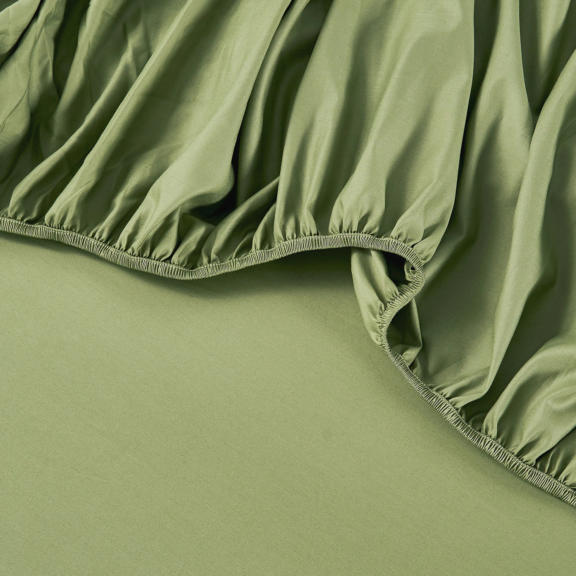 Close-up view of JELLYMONI Soft Cool Cotton Sateen Sheets in green, showcasing the soft, breathable fabric and elastic band of the fitted sheet.