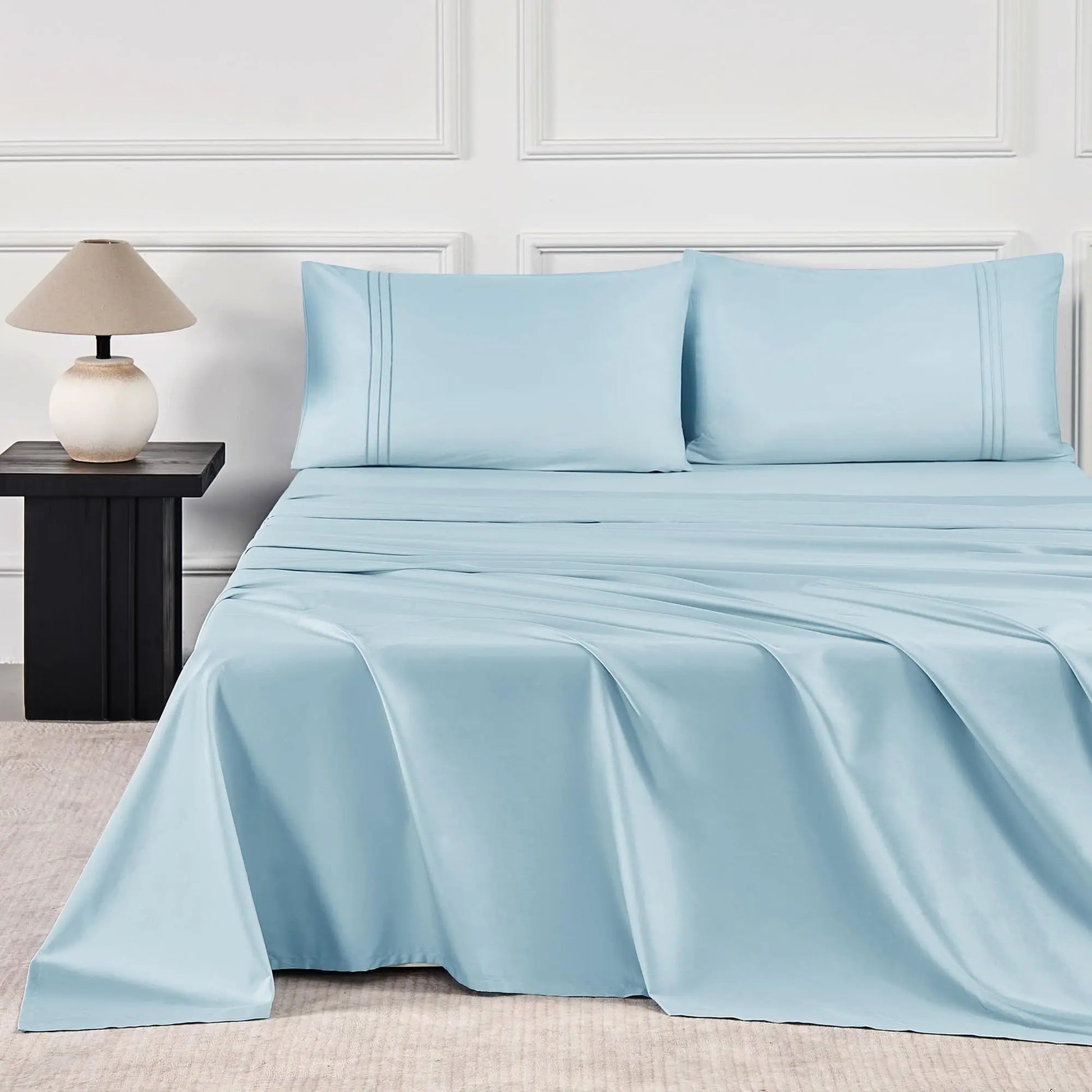 JELLYMONI Soft Cool Cotton Sateen Sheets in a refreshing blue color, elegantly laid out on a well-appointed bed next to a chic nightstand.