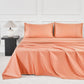 JELLYMONI Soft Cool Cotton Sateen Sheets in vibrant coral, creating a warm and inviting bed atmosphere with coordinating pillows and a lamp.