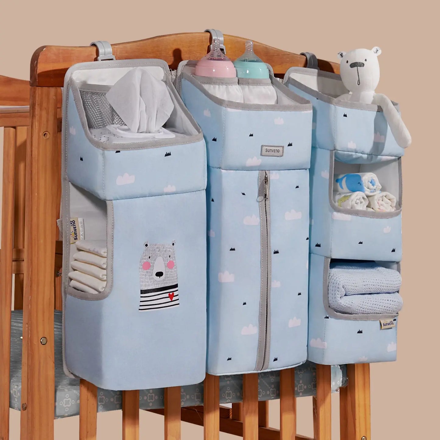 Sunveno Crib Organizer Baby Essentials Within Reach hanging on a crib with multiple compartments, containing diapers, bottles, and baby toys, ideal for nursery organization.