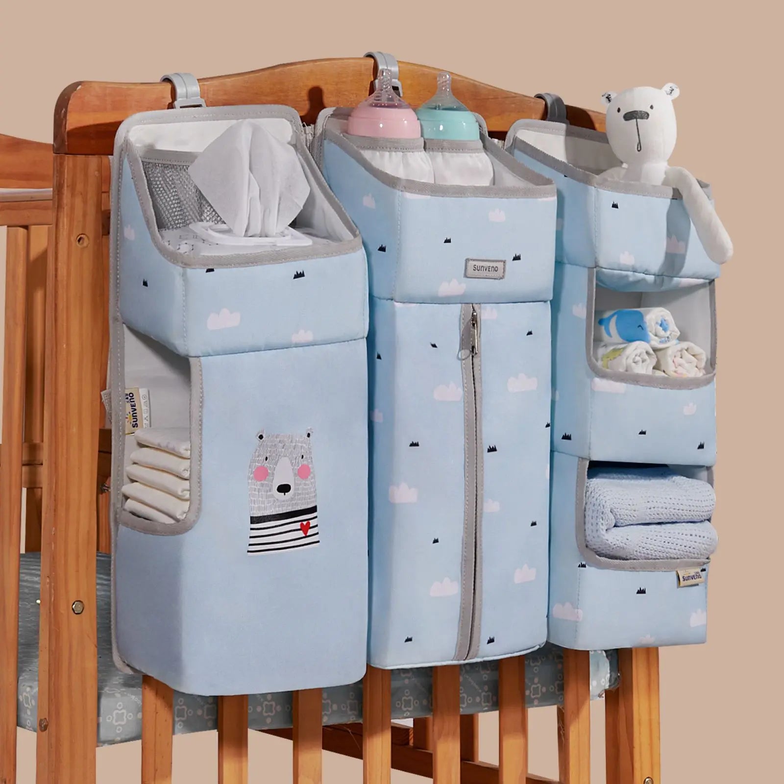 Sunveno Crib Organizer Baby Essentials Within Reach hanging on a crib with multiple compartments, containing diapers, bottles, and baby toys, ideal for nursery organization.