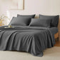 Trendy gray JELLYMONI Soft Cool Cotton Sateen Sheets styled on a comfortable bed, complemented by decorative pillows and a casual coffee setting.
