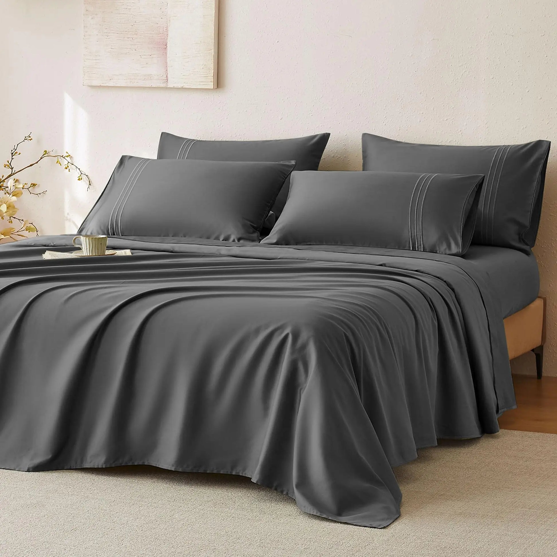 Trendy gray JELLYMONI Soft Cool Cotton Sateen Sheets styled on a comfortable bed, complemented by decorative pillows and a casual coffee setting.