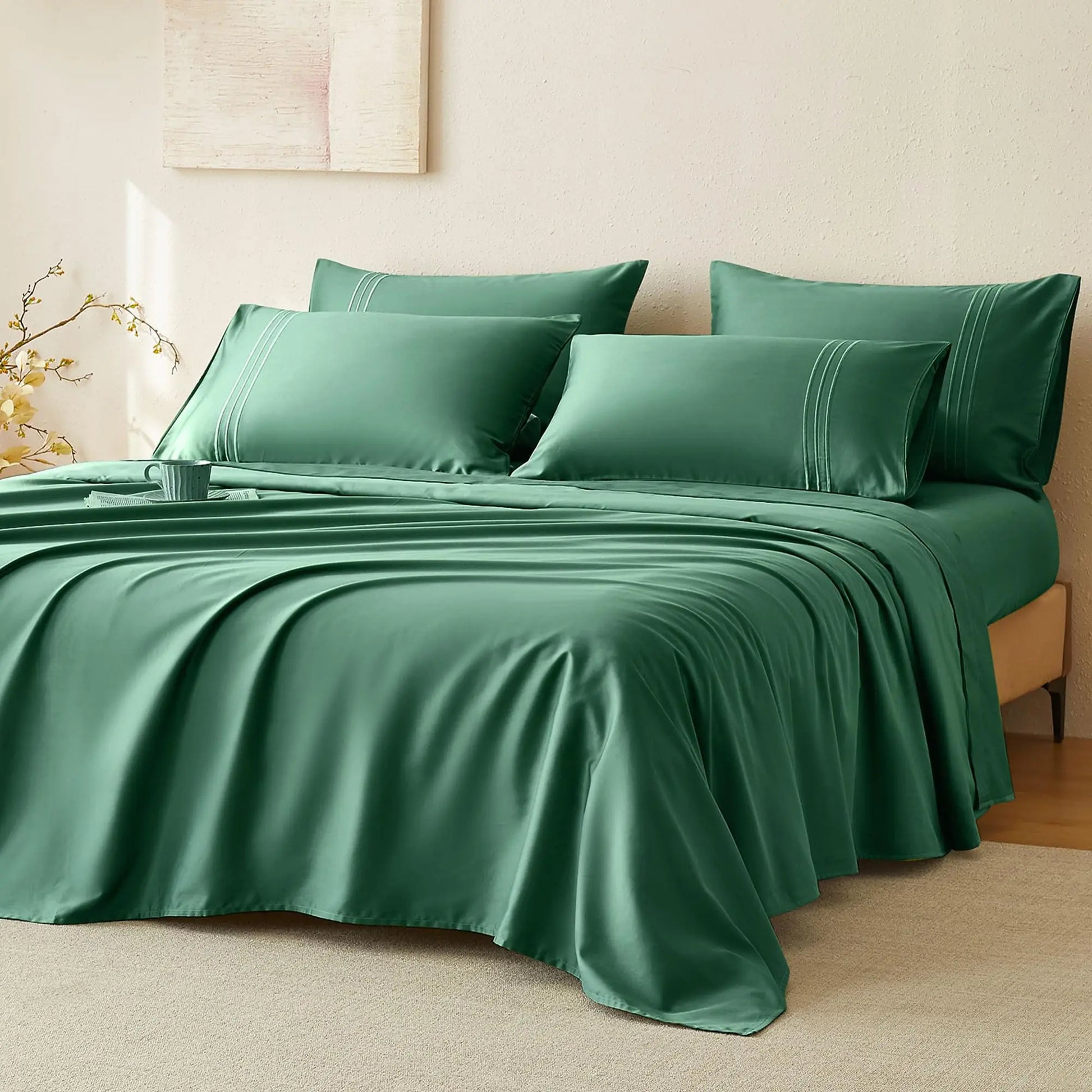 JELLYMONI Soft Cool Cotton Sateen Sheets in a rich green hue, beautifully draped over a bed surrounded by decorative pillows, adding a touch of elegance.