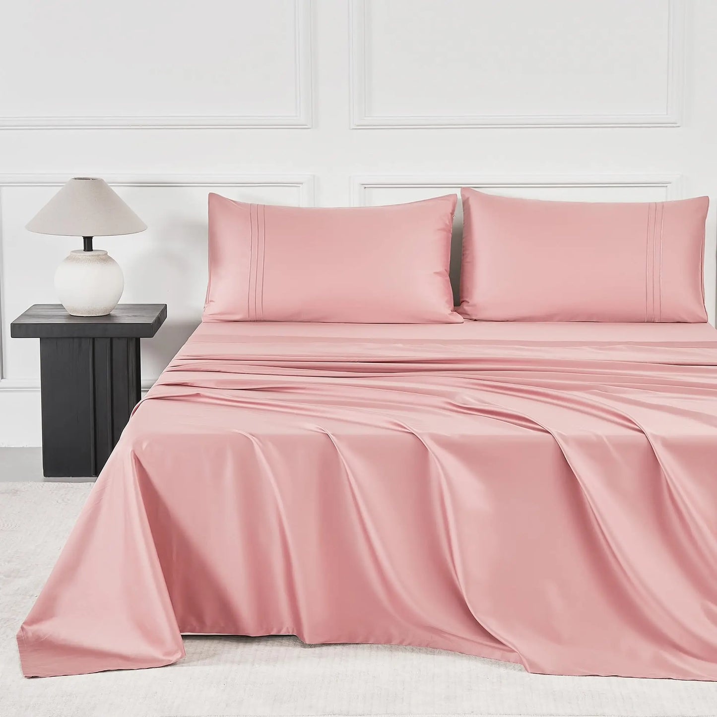 JELLYMONI Soft Cool Cotton Sateen Sheets in a lovely pink shade, showcasing a cozy bed setup complete with plush pillows and a stylish lamp.