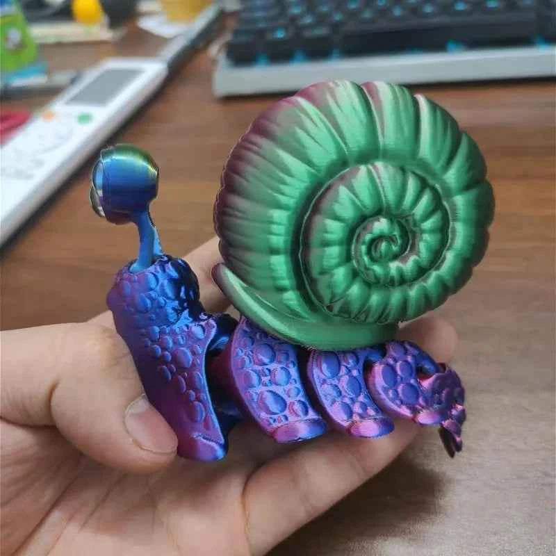Colorful articulated 3D printed snail toy with a green shell and purple body, held in a hand